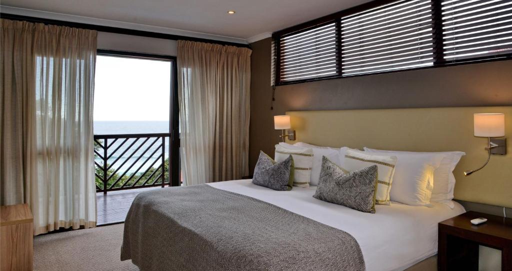 a bedroom with a large bed and a balcony at ANEW Hotel Ocean Reef Zinkwazi in Zinkwazi Beach