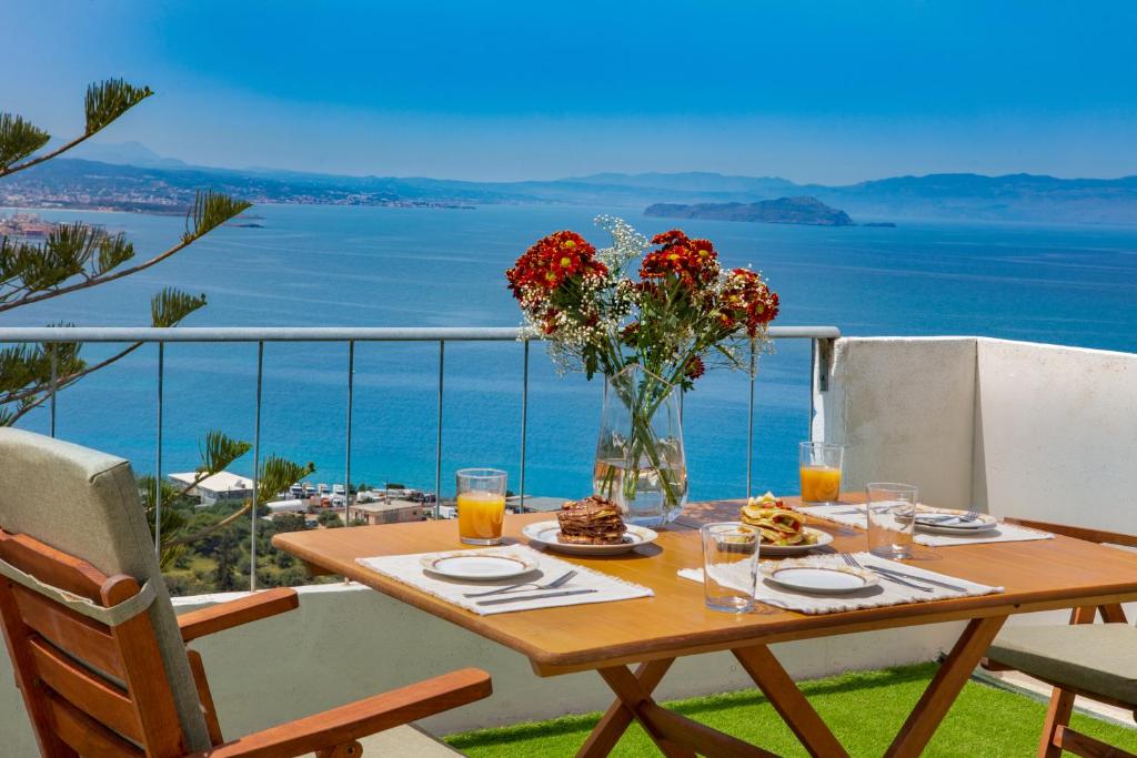 una mesa con un jarrón de flores en el balcón en Sunset Home with sea view en La Canea