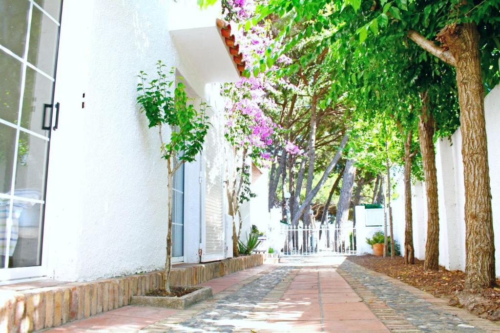 a street with trees and flowers on a white building at Lovely villa next to the beach in Cambrils