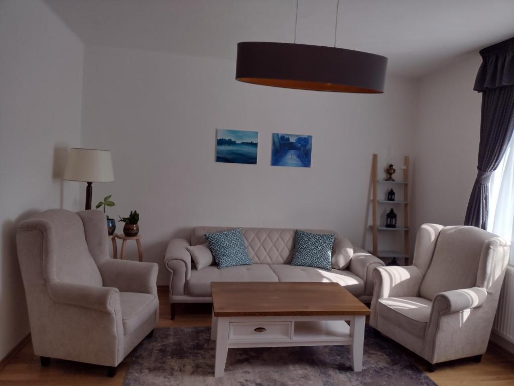 uma sala de estar com um sofá e duas cadeiras e uma mesa em Bara ház em Tvrdošovce