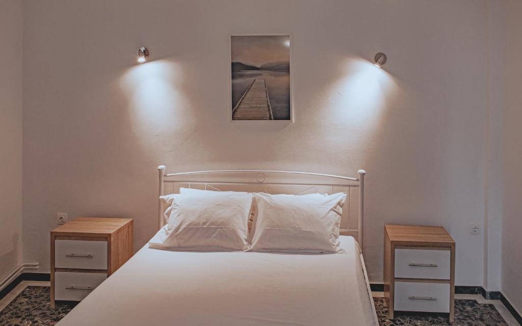 a bedroom with a white bed with two night stands at Modern apartment 1 minute from Remataki beach in Samos
