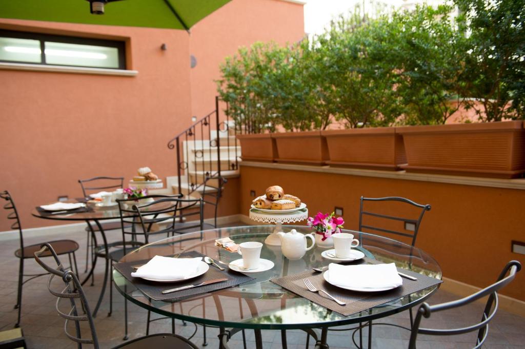 two tables and chairs on a patio with flowers at Artemis Hotel in Cefalù