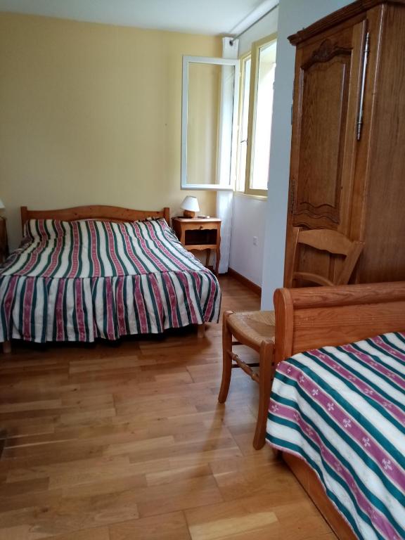 a bedroom with two beds and a chair and a window at la Bergerie in Tréméreuc
