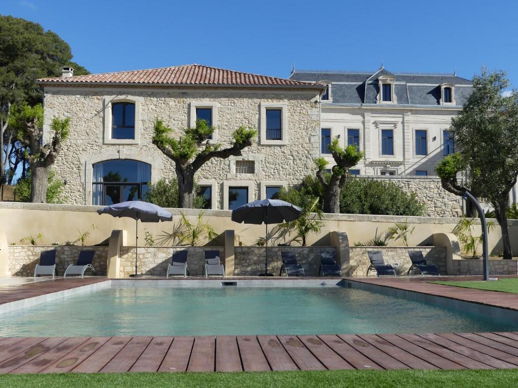 una piscina con sedie e ombrelloni di fronte a un edificio di Domaine de la Vidalle a Vendres