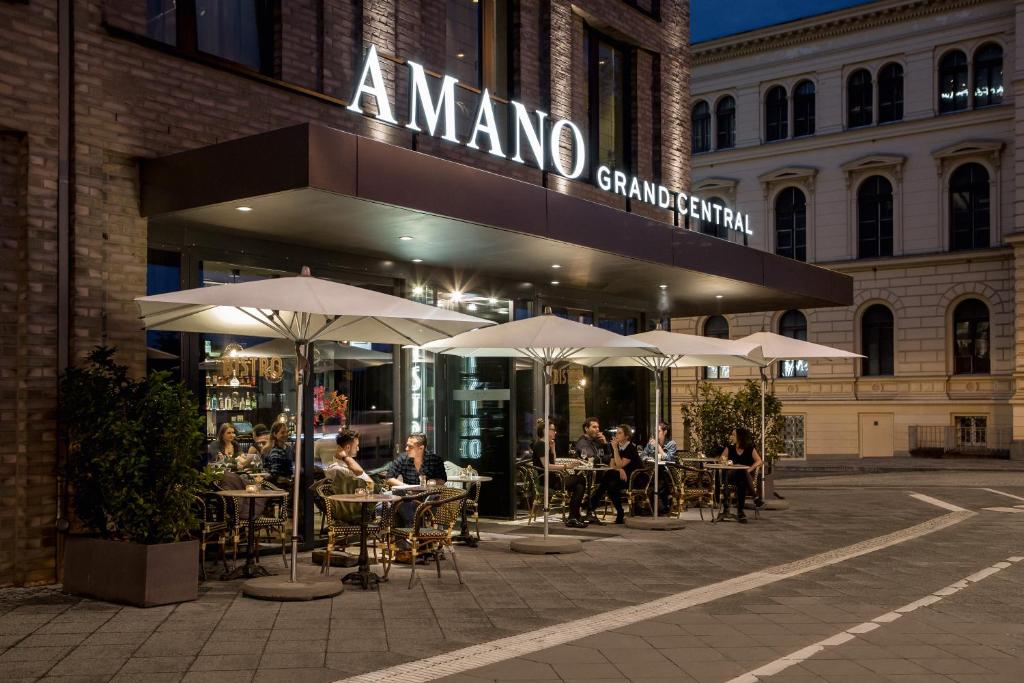 a group of people sitting at tables outside a restaurant at Hotel AMANO Grand Central in Berlin