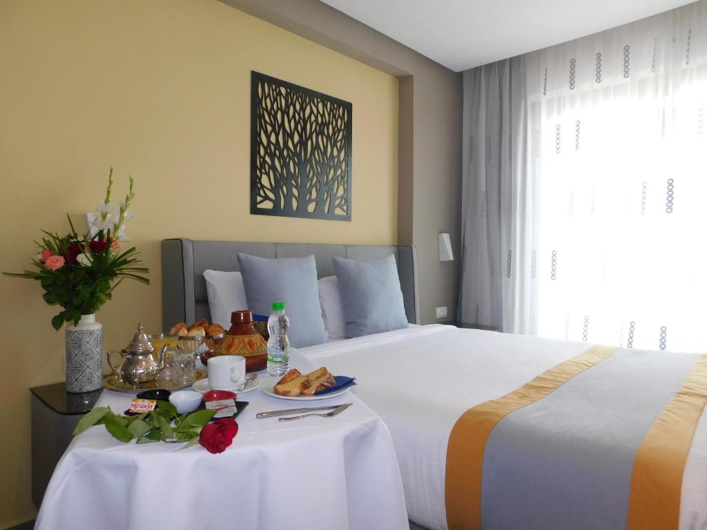 una habitación de hotel con una cama con una mesa con comida. en Gardenia Boutique Hotel en Rabat