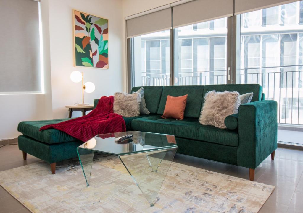 a living room with a green couch and a glass table at Brand New 2BR in Park Heights 212 in Dubai