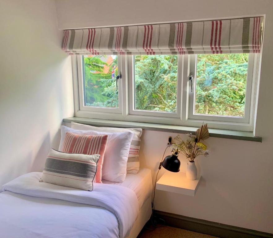 um quarto com uma cama com almofadas e uma janela em The Cottage, Yew Tree Farm Holidays, Tattenhall, Chester em Tattenhall