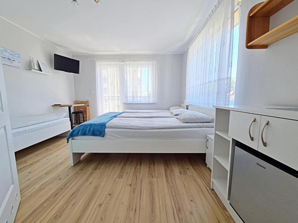 a white bedroom with a bed and a wooden floor at Chatka Morska 3 in Karwia