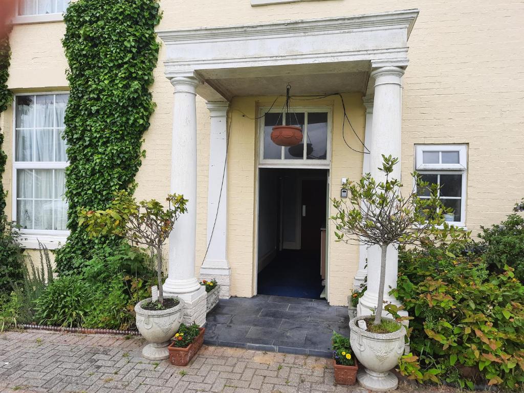 a yellow house with a front door with two plants at Self Contained apartment in Winterton Hall in Great Yarmouth