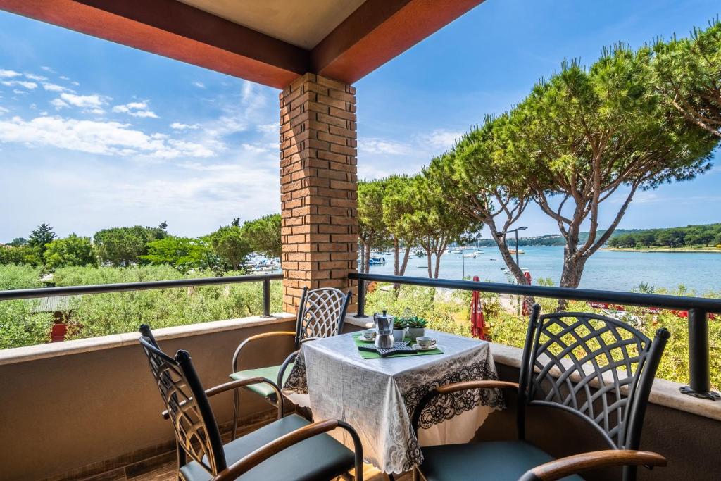 a table and chairs on a balcony with a view of the water at Apartments Oliveto in Medulin