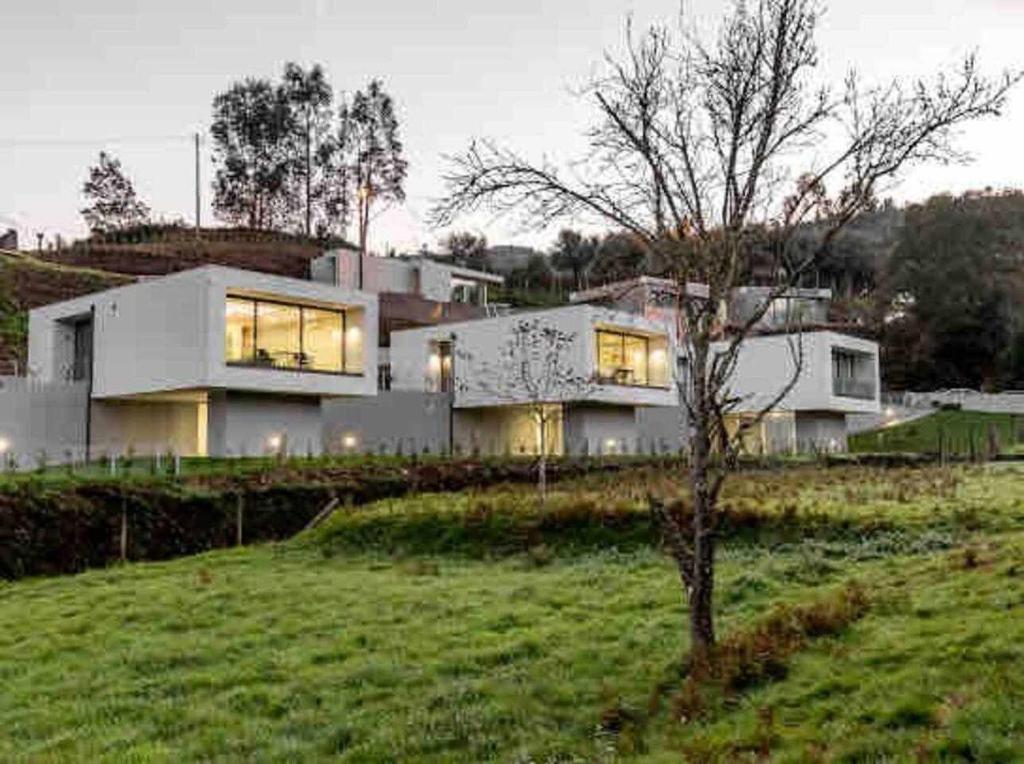 una gran casa blanca en la cima de un exuberante campo verde en Viana do Castelo - Amonde Village Casa P - Conforto Qualidade Natureza, en Amonde