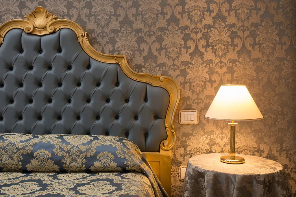 a bedroom with a bed with a headboard and a lamp at palazzo suite ducale in Venice