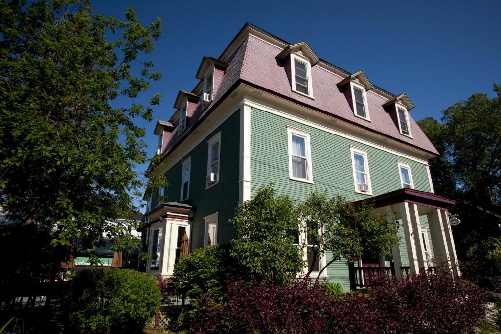 duży zielony dom z fioletowym dachem w obiekcie Le Pleasant Hôtel & Café w mieście Sutton