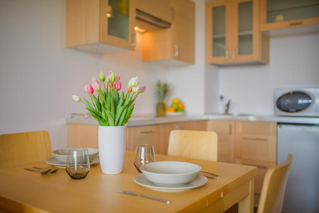 a kitchen table with a vase of flowers on it at Apartament Madam in Stegna
