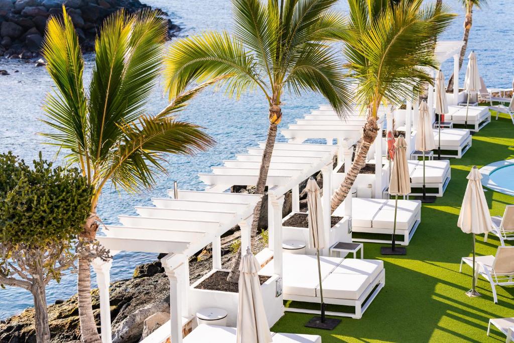 a row of white chairs and palm trees at a resort at Hotel LIVVO Puerto de Mogán in Puerto de Mogán