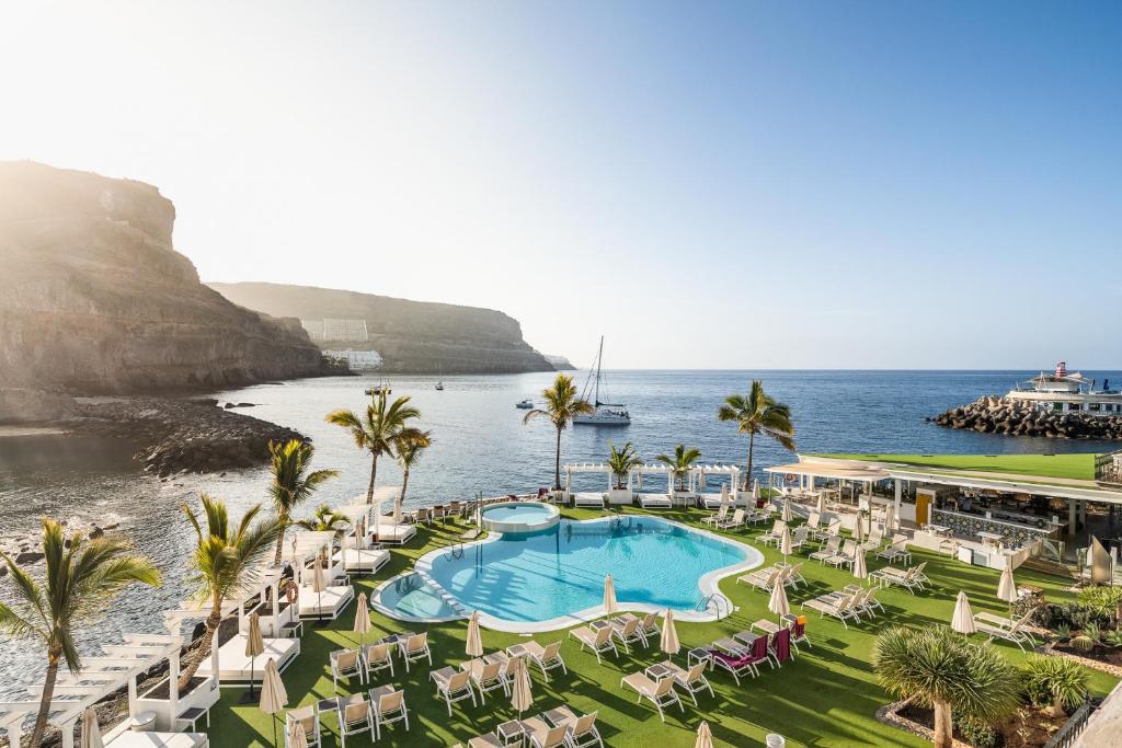 an aerial view of a resort with a pool and the ocean at Hotel LIVVO Puerto de Mogán in Puerto de Mogán