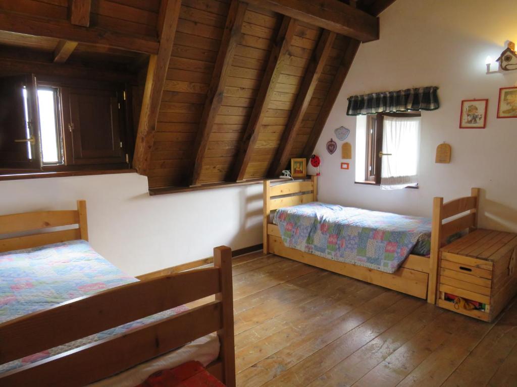 a bedroom with two beds and wooden floors at tipica baita con vista sul monte magnola in Ovindoli