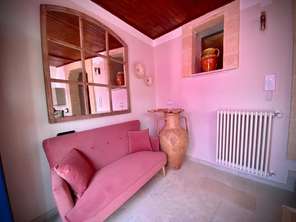 ein Wohnzimmer mit einer rosa Couch und einer Vase in der Unterkunft Le Dimore in Piazzetta in Massafra