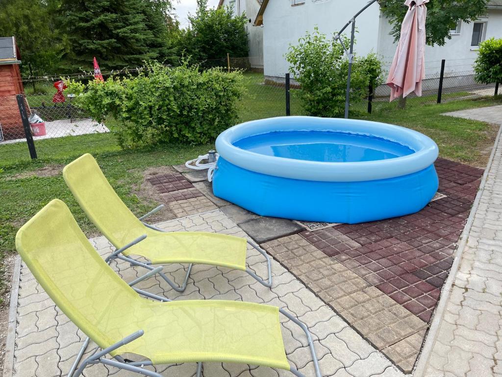 2 sillas y una piscina en el patio trasero en Ágnes Nyaralóház, en Balatonmáriafürdő