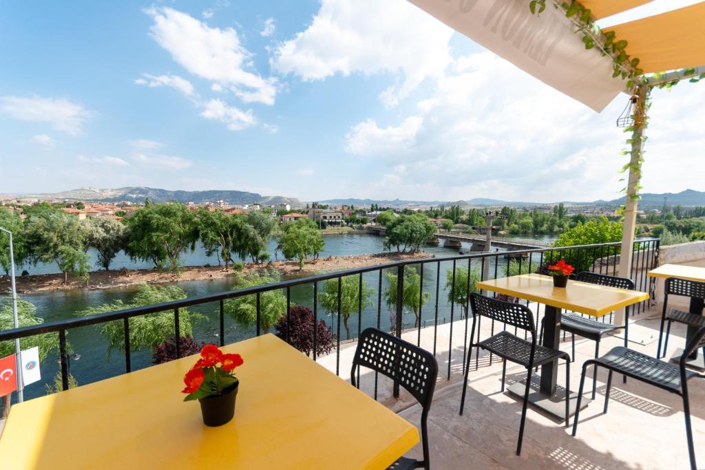 a balcony with tables and chairs and a view of a river at Lemon Cave Suites in Avanos