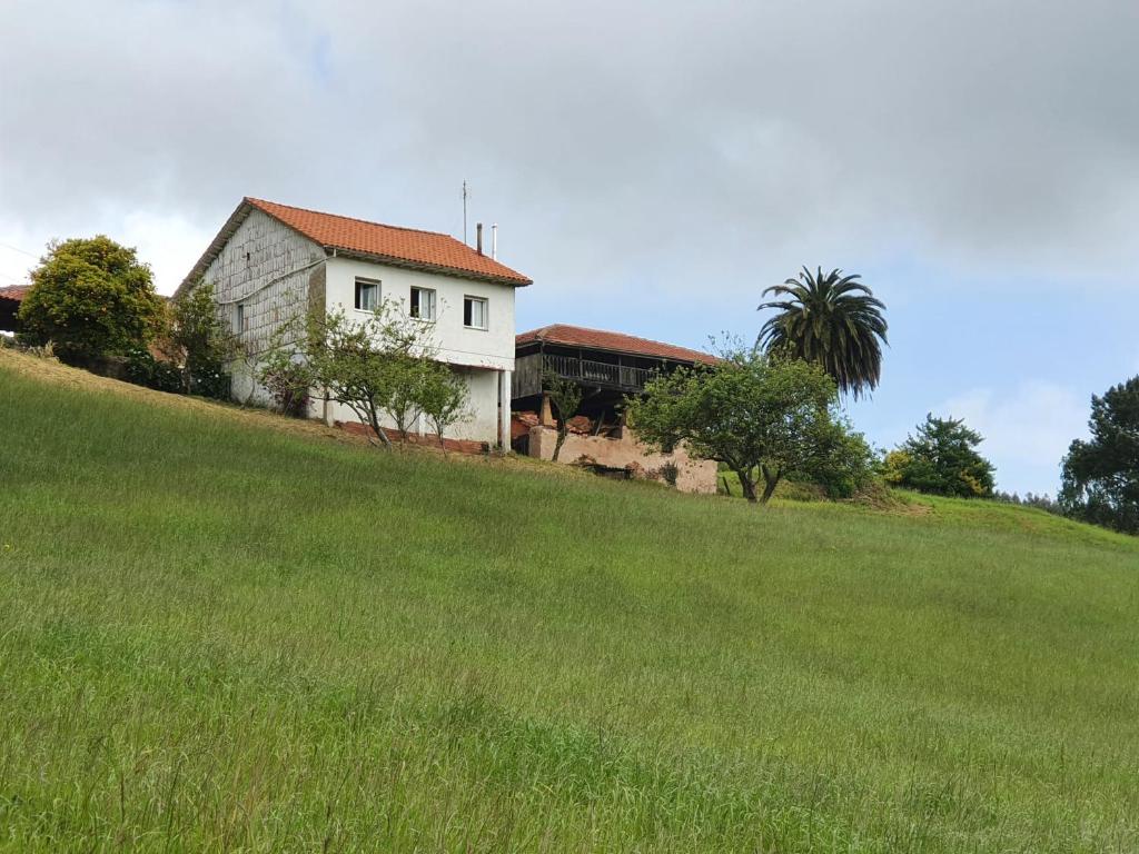 une maison blanche sur une colline avec un champ vert dans l'établissement Casa Don Diego, à Perlora