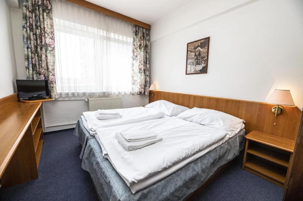 Schlafzimmer mit einem Bett, einem Schreibtisch und einem Fenster in der Unterkunft Hotel Astra in Prag