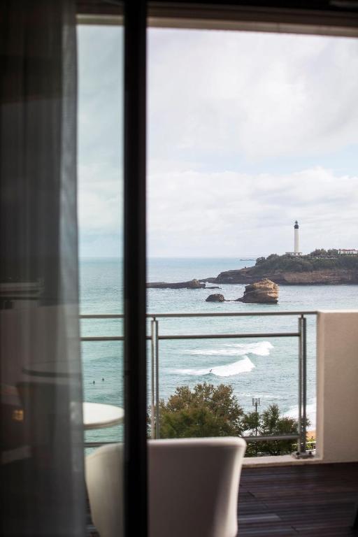 a window with a view of the ocean and a lighthouse at Hôtel Le Café de Paris in Biarritz