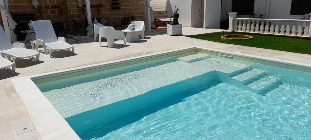 een groot zwembad met stoelen en een patio bij B&B Cinque Stelle Salento in Marina di Mancaversa