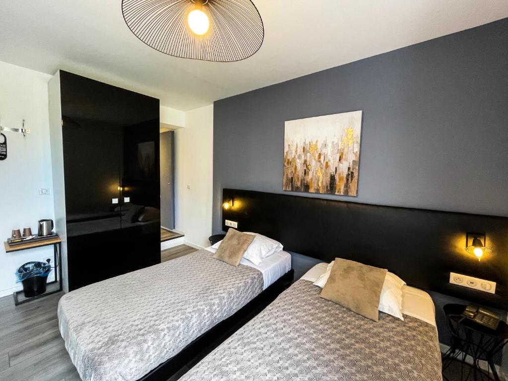a hotel room with two beds and two lamps at Hôtel et Appartement "Le Maguy" in Cassis