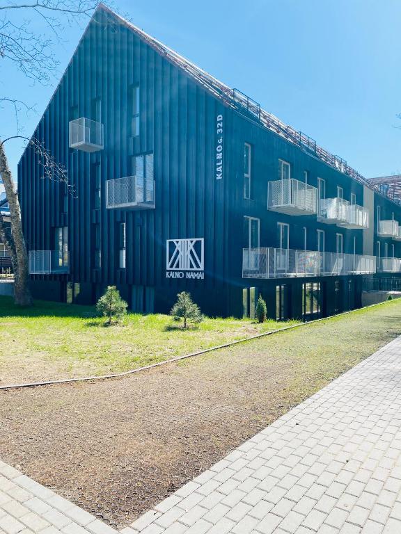 耶德库安特Rimos apartamentai Juodkranteje的一座蓝色的大建筑,其一侧设有窗户