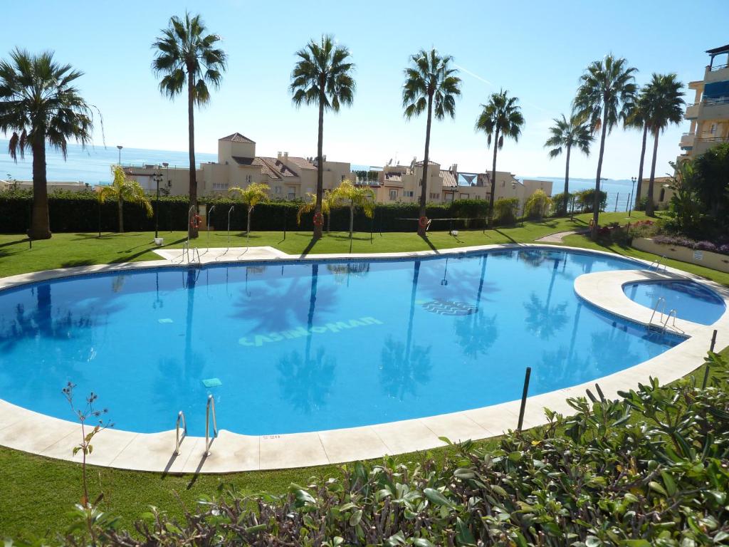 une grande piscine avec des palmiers en arrière-plan dans l'établissement Casinomar, à Benalmádena