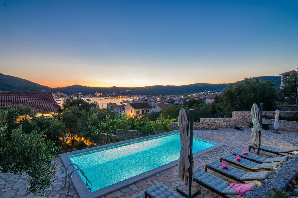 a pool with chairs and a view of a city at Skoro Residence in Vinišće