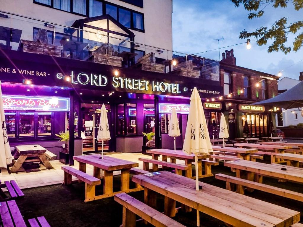 紹斯波特的住宿－The Lord Street Hotel; BW Signature Collection，一组野餐桌,在建筑前摆放着雨伞