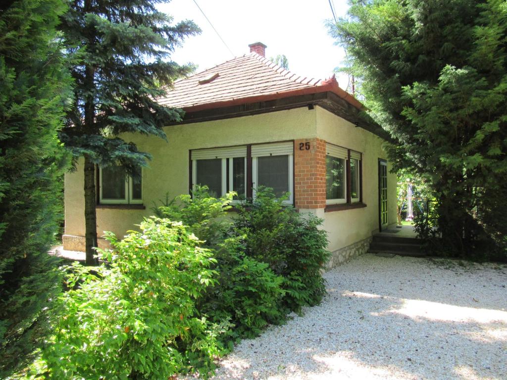 uma pequena casa com arbustos à frente em Aranyalma Vendégház em Gárdony
