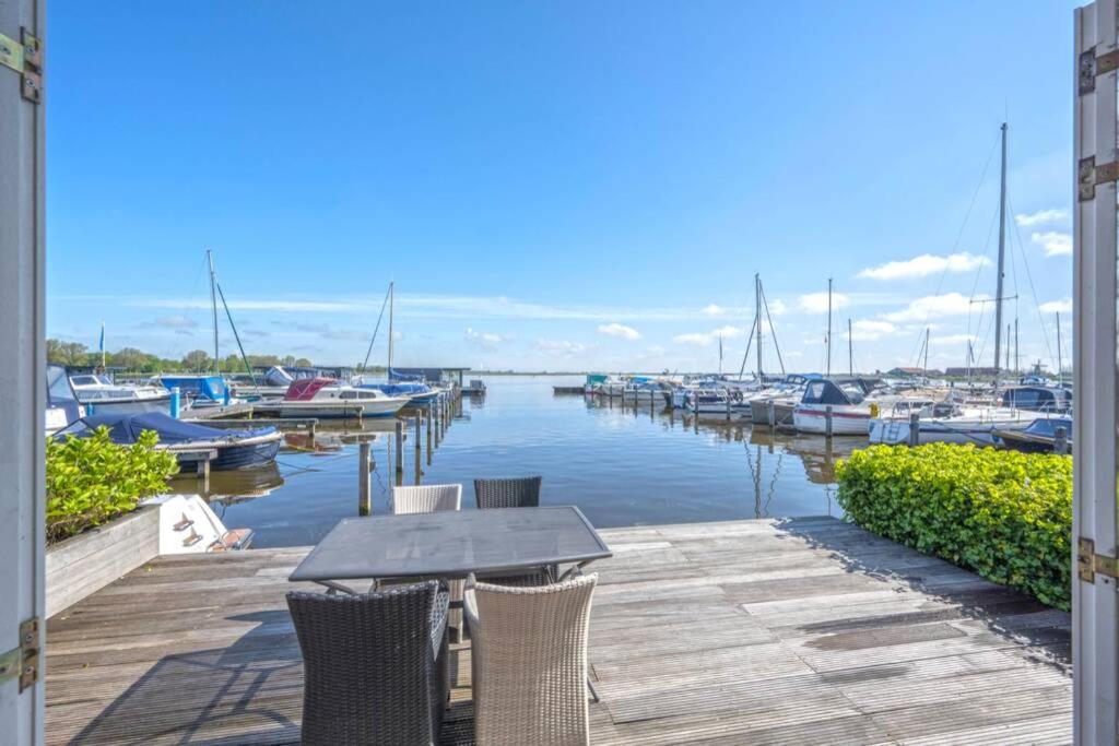 une table et des chaises sur un quai avec des bateaux dans l'eau dans l'établissement Meerzicht 20 - Waanzinnig uitzicht over het water!, à Uitgeest