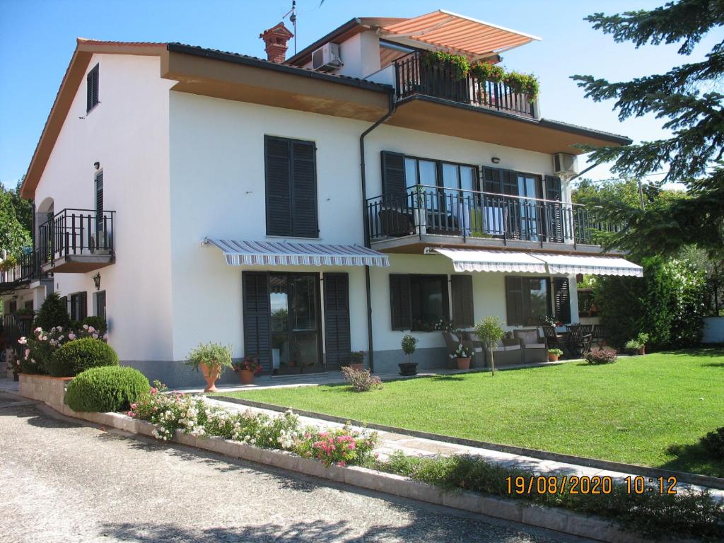 a large white house with balconies and a yard at ALIANA apartment in Sečovlje