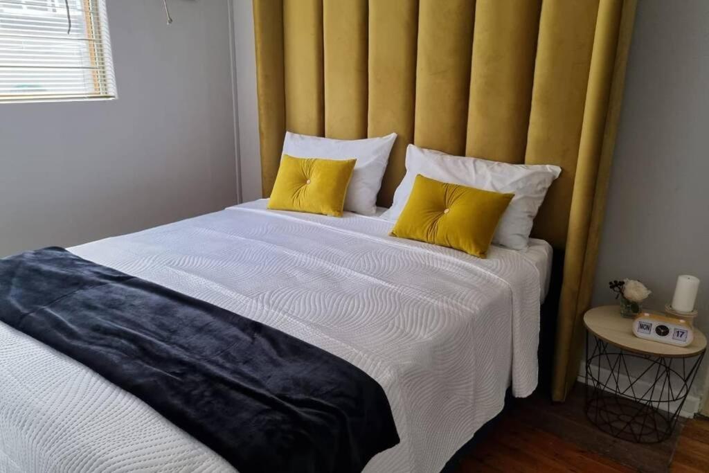 a bedroom with a large bed with a yellow headboard at 9th Green, Mill Park in Glendinningvale
