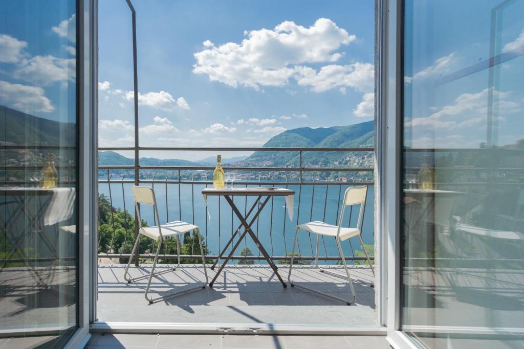 una mesa y sillas en un balcón con vistas al agua en La Casa dell'Architetto by Rent All Como en Blevio