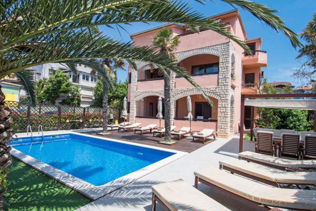 a villa with a swimming pool and palm trees at Anita apartment in Medulin