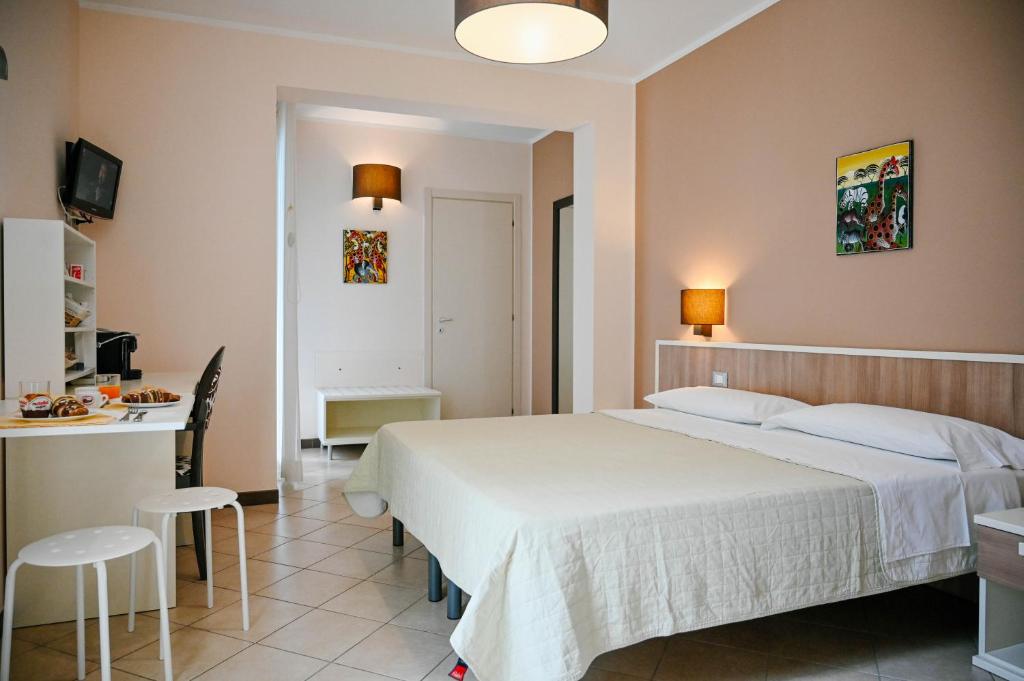 a bedroom with a white bed and a kitchen at Stella del Sud in Avola