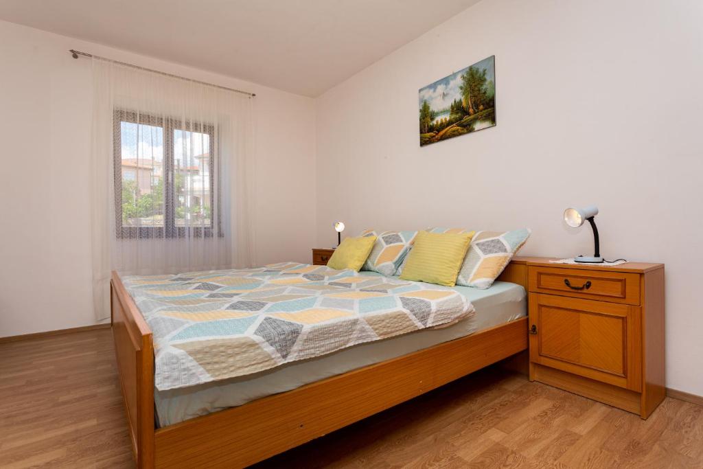 Schlafzimmer mit einem Bett, einem Nachttisch und einem Fenster in der Unterkunft Apartment Mira Šilo-Krk in Šilo