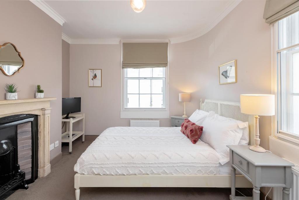 a white bedroom with a bed and a fireplace at Monmouth Street Bath in Bath