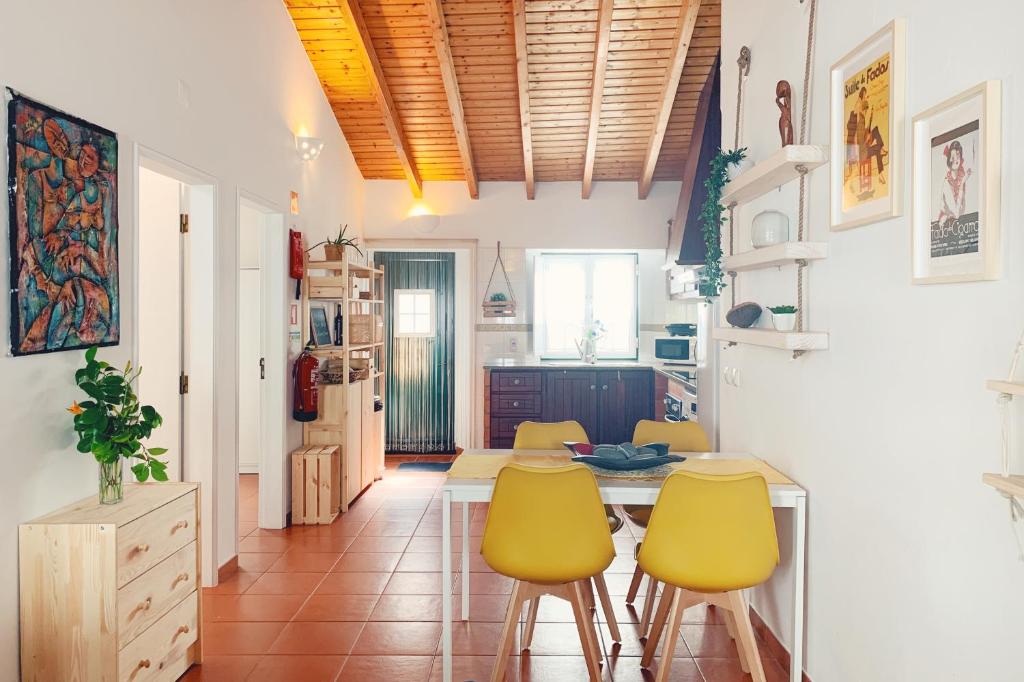 a kitchen with a table and four yellow chairs at Casa da Vila in Odeceixe
