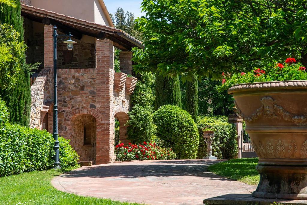 ein Backsteinhaus mit einer großen Vase im Hof in der Unterkunft Il Torrino Country Resort in Montaione