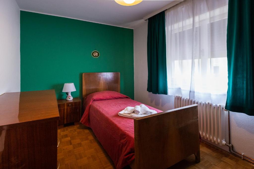 una camera da letto con pareti verdi e un letto con una coperta rossa di La Marmote Albergo Diffuso di Paluzza Naunina a Paluzza
