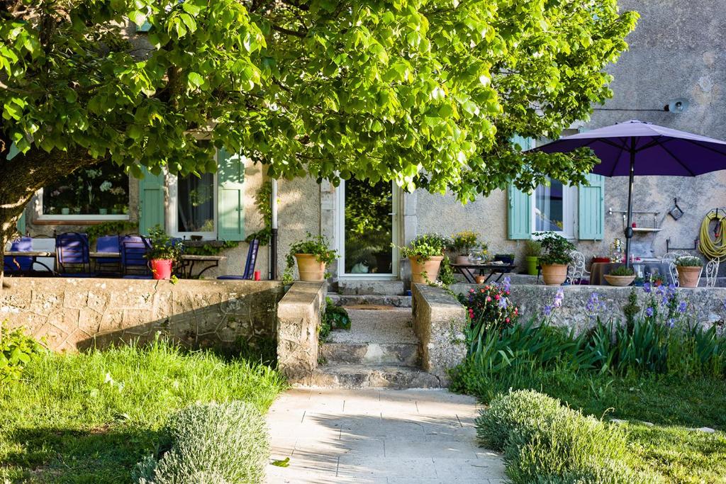 a house with a porch and an umbrella in the yard at La Grande Maison De Nans in Nans-les-Pins