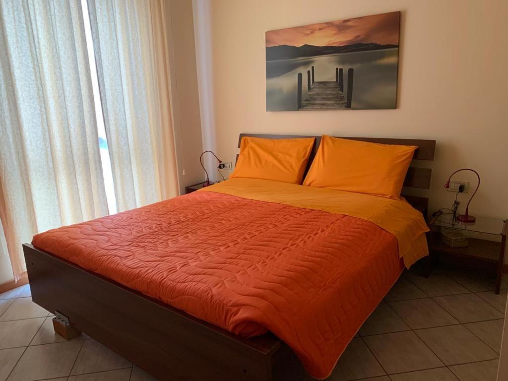 ein Schlafzimmer mit einem Bett mit einer orangefarbenen Bettdecke in der Unterkunft Holiday House Boschette in San Felice del Benaco