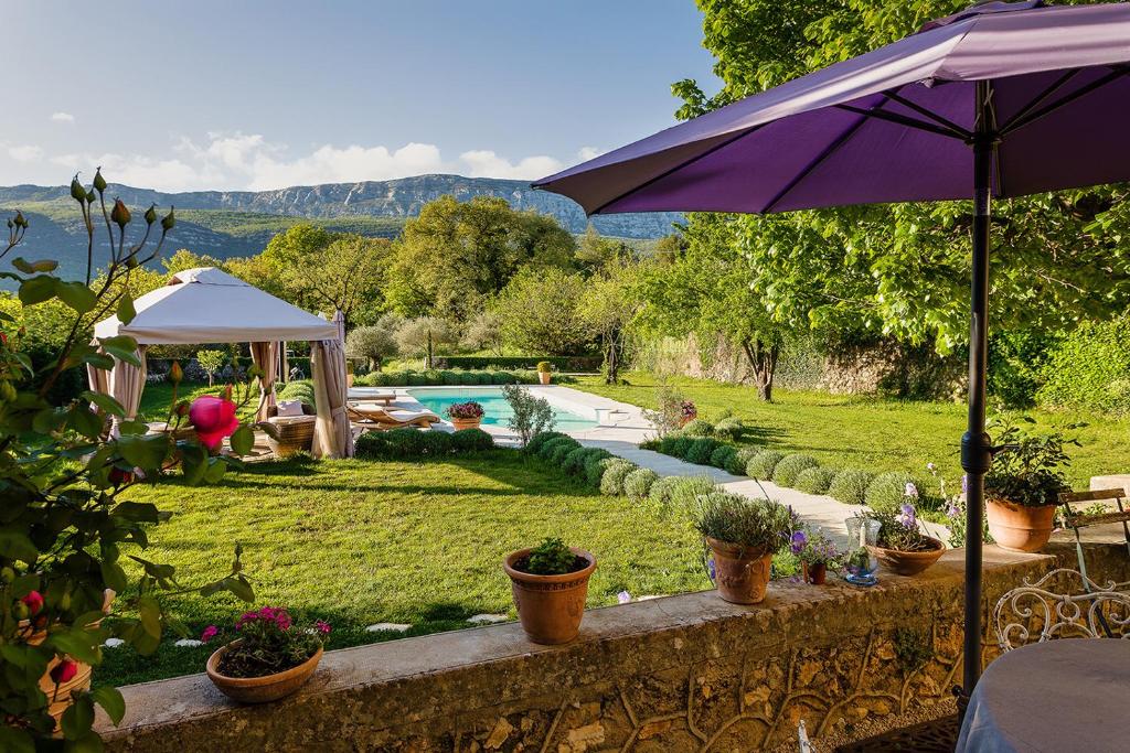 a garden with a swimming pool and an umbrella at La Grande Maison De Nans in Nans-les-Pins