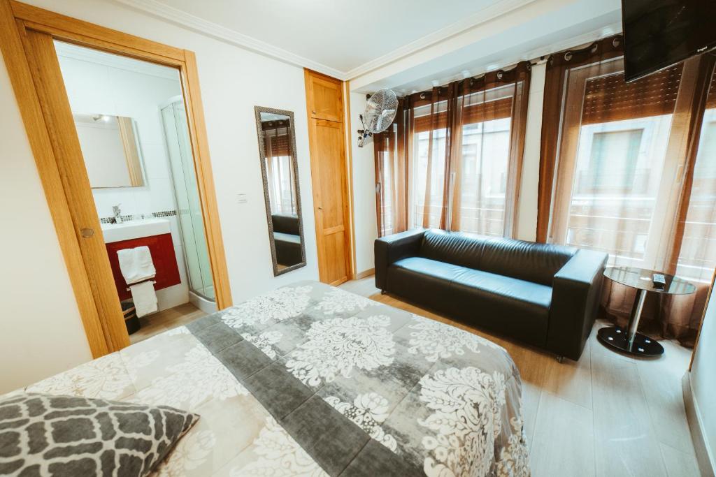 um quarto com uma cama, um sofá e janelas em Hospederia Rincon De Leon em Leão